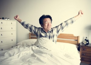 Middle-aged man stretches in bed after his insomnia has been helped by CBT-1 treatment at Synergy Counselling Kamloops